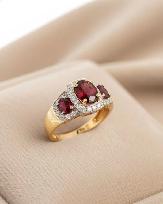 Gold ring with red gemstones on a beige surface