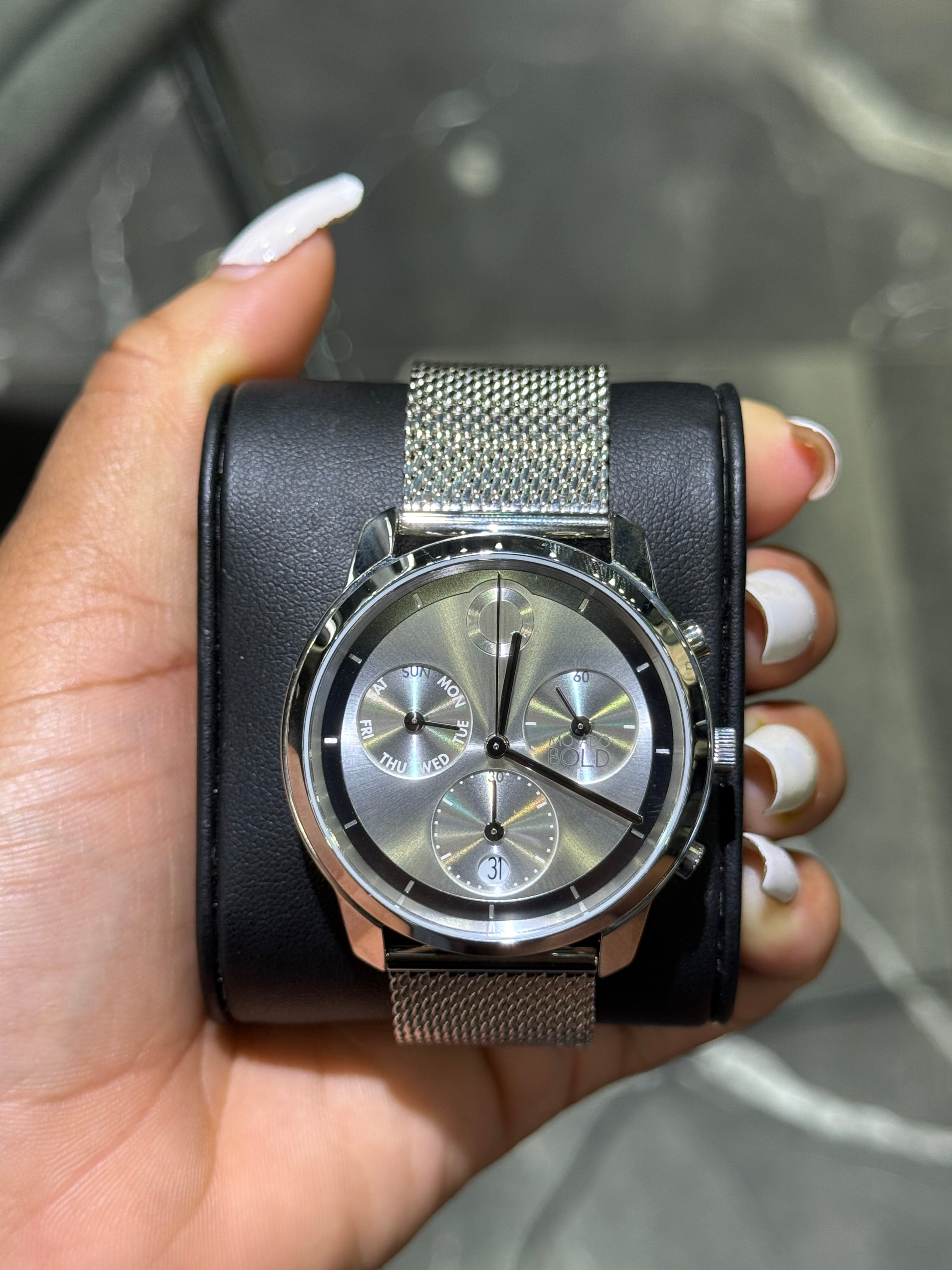 Hand holding a black and silver watch with a textured band